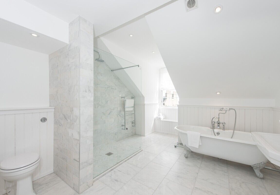 Un bagno moderno con cabina doccia in vetro, vasca da bagno indipendente e water.