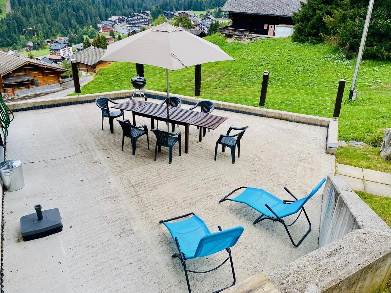 Un patio con mesa y sillas, una parrilla y un sillón azul.