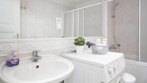 A modern bathroom with a white sink, a mirror, a shower, and a toilet. - Pretty, comfortable apartment (Praga)