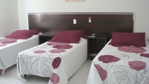 A hotel room with two single beds, each with a headboard and a bedside table.