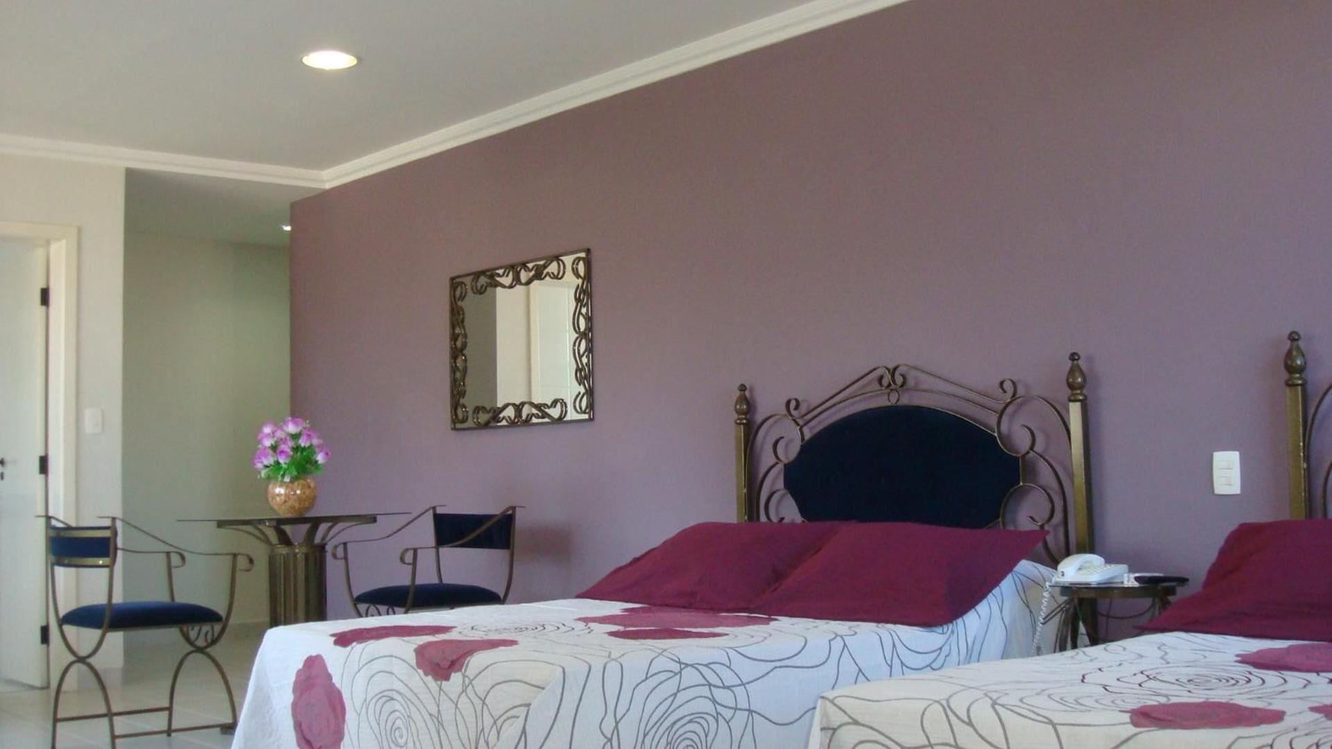 Una habitación de hotel con una cama, una silla, un escritorio y un espejo.