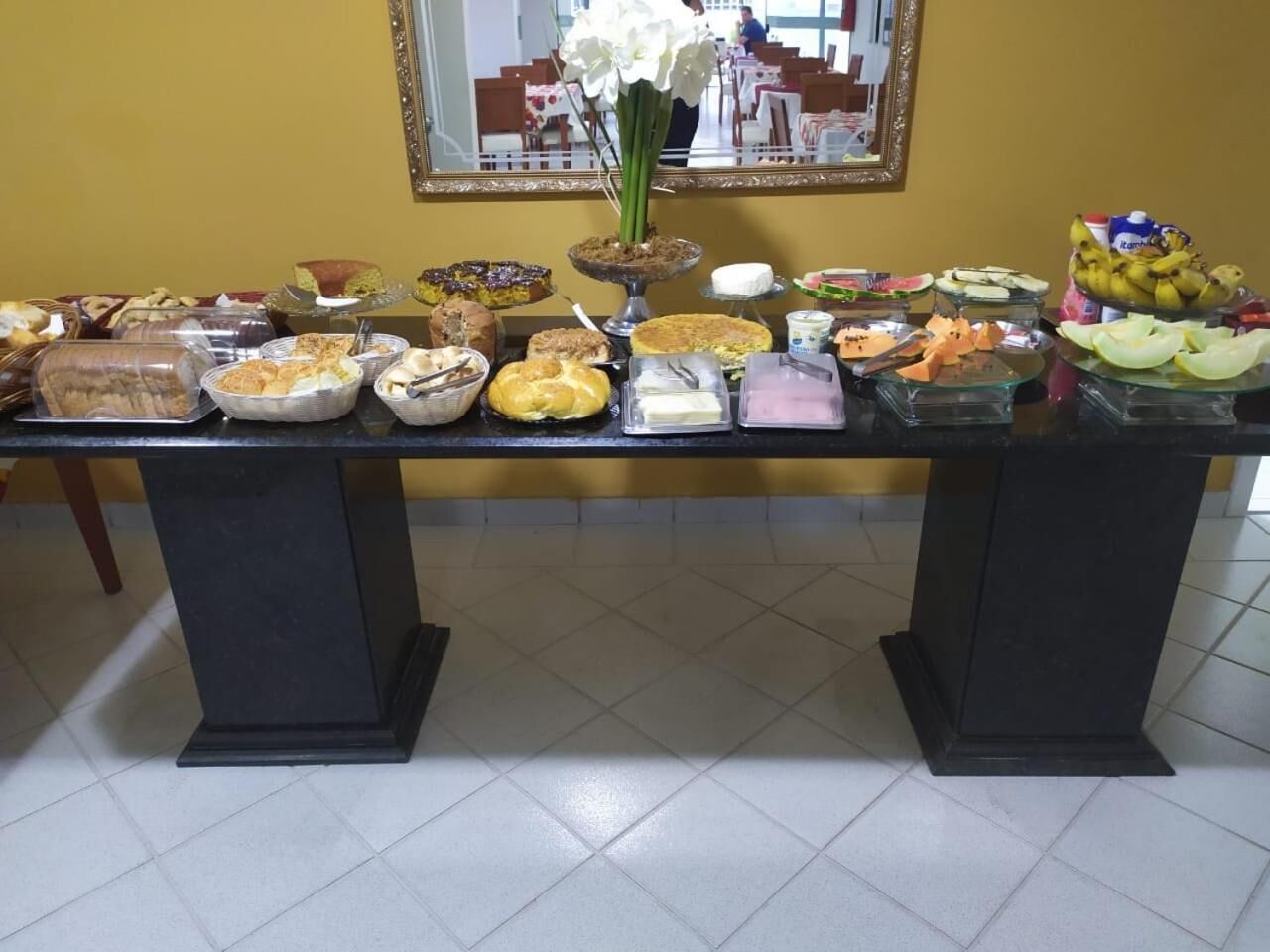 Mesa de buffet com diversos alimentos e um espelho na parede.