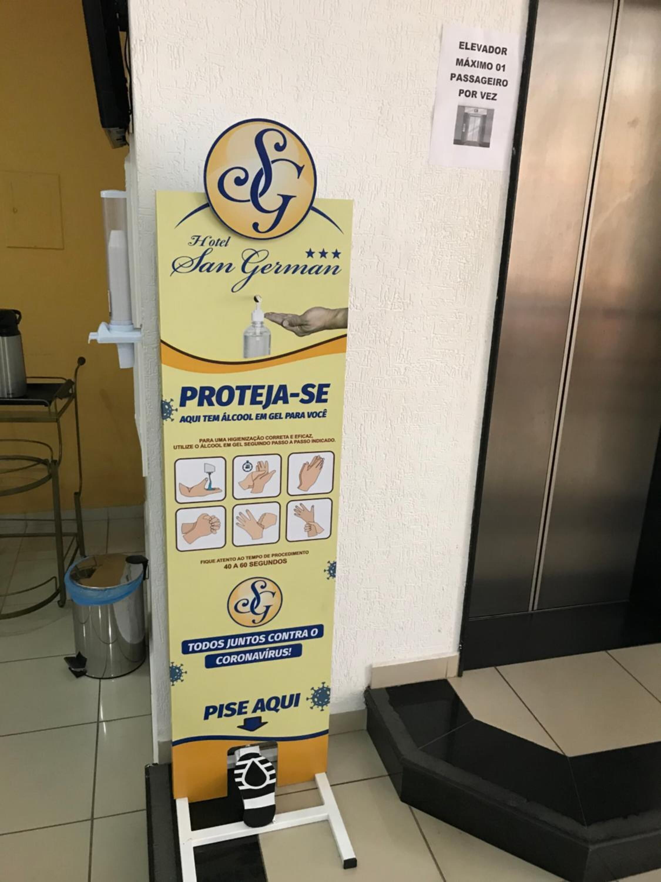 A hygiene promotion stand in a hotel lobby with instructions for hand sanitization.