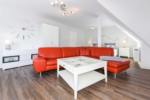 Un salon moderne avec un canapé rouge, une table basse blanche et un meuble blanc.