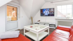 En moderne stue med en rød sofa, et hvidt sofabord og et fjernsyn monteret på væggen.