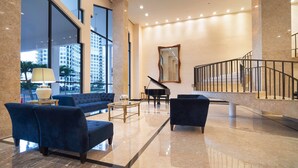A spacious lobby with a grand piano, plush seating, and a large mirror. - Ocean Grand Residences (Miami Beach)