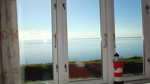 A view through a window with a white frame and a red and white lighthouse in the foreground. - Wunderbares Haus nur 20 Meter vom Wasser mit riesengroßes Grundstück! Herrlich. (Dänemark)