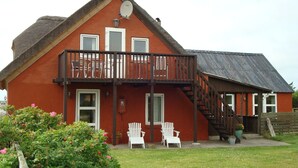 A red house with a balcony, two white chairs, and a staircase leading to an upper level. - Wunderbares Haus nur 20 Meter vom Wasser mit riesengroßes Grundstück! Herrlich. (Dänemark)