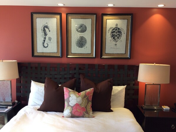 Une chambre d’hôtel comprenant un lit, deux tables de chevet et trois œuvres d’art encadrées accrochées au mur.