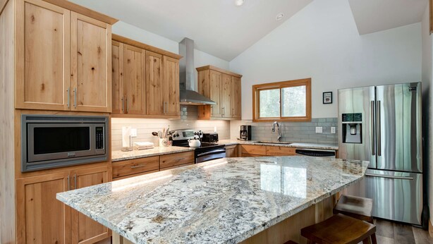 Una cocina con armarios de madera, un refrigerador de acero inoxidable, una encimera de granito y un horno empotrado.