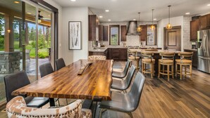 A modern kitchen with a large island, dark wooden cabinets, and a stone accent wall.