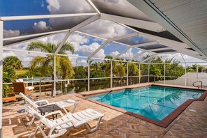 An outdoor swimming pool with a covered area, lounge chairs, and a view of the surrounding landscape.