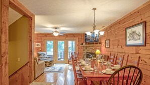 A wooden cabin interior with a dining area, wooden walls, a fireplace, and a ceiling fan. - Loggers Run #7: 5 BR, 3.5 BA: Slope Side. Hot Tub, Overlooks Ski Trail! (Snowshoe)