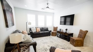 A living room with a black leather sofa, a wooden coffee table, a patterned rug, and a mounted TV. - ⛏️ Red Rock ⛏️ Adventurous Desert Experience | POOL IS OPEN!!! (Washington)