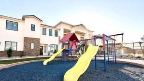 A playground with slides and climbing structures, surrounded by a landscaped area with a building in the background. - ⛏️ Red Rock ⛏️ Adventurous Desert Experience | POOL IS OPEN!!! (Washington)