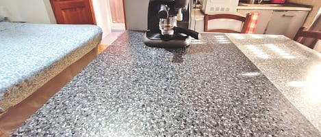 A kitchen with a coffee maker on a granite countertop.