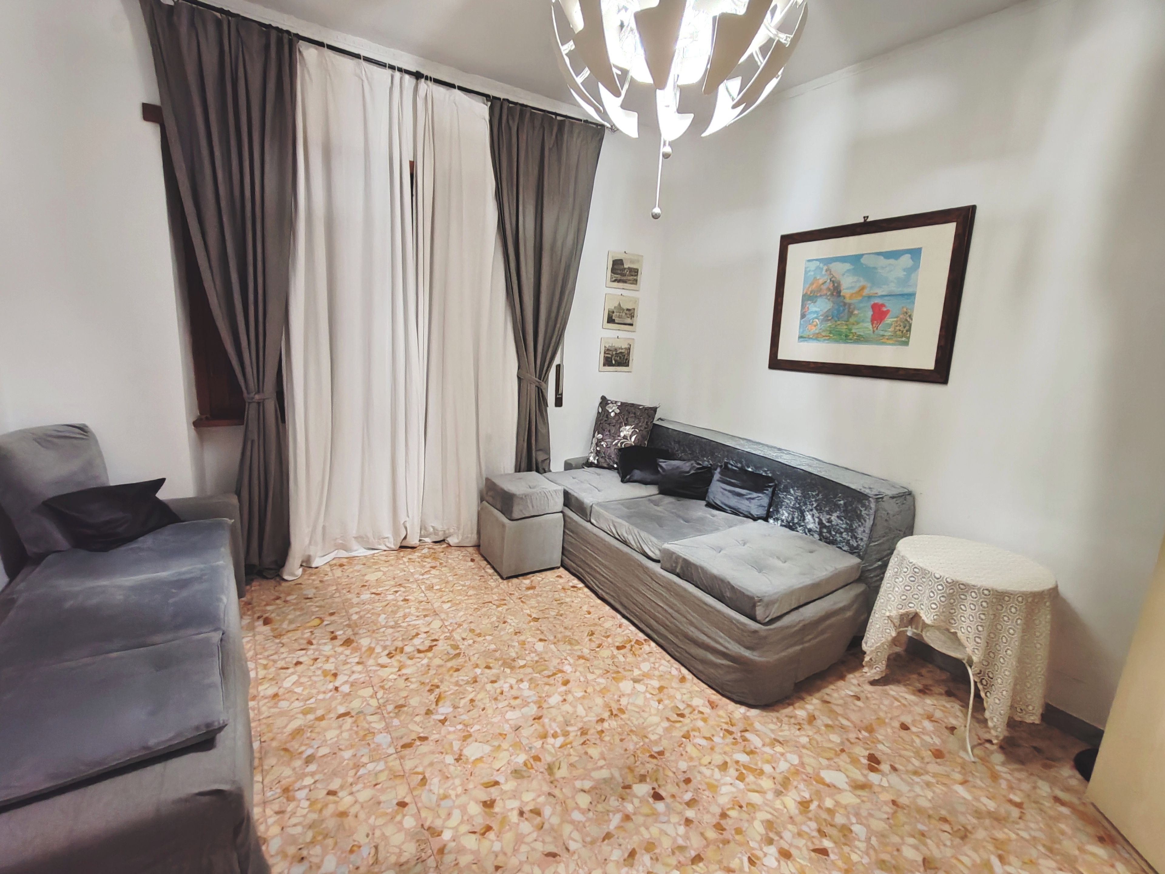 A modern living room with a sofa, a small table, and a decorative ceiling light.