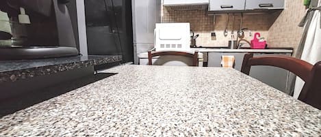 Une cuisine dotée de plans de travail en granit, de meubles blancs et d’une hotte de cuisinière en acier inoxydable.