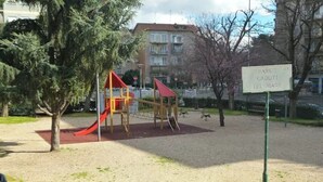 A playground with a red slide and climbing structures, surrounded by trees and a gravel area. - Apartment in the heart  of Rome free fast  wi fi (Roma)
