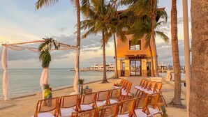 A beachside wedding setup with wicker chairs and a white canopy.