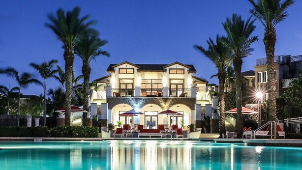 A large, two-story hotel with a swimming pool in front.