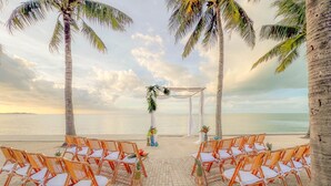 A beach wedding setup with chairs and a decorated arch.