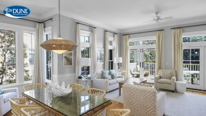 A spacious living area with a glass dining table, wicker chairs, a sofa, and a patterned armchair. Large windows offer views of the outdoors. - * Beautiful 2 BR * WaterColor * 6 WaterColor Blvd #201 * Steps to Beach Club (Santa Rosa Beach)