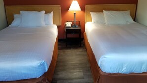 Une chambre d’hôtel avec deux lits, une table de chevet avec une lampe et un téléphone.