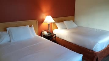 Una habitación de hotel con dos camas, una mesita de noche con lámpara y un teléfono.