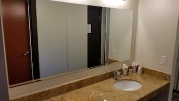 Un baño con un espejo grande, un lavamanos y una puerta.