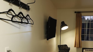 Une pièce équipée d’un four à micro-ondes, d’une table, d’une chaise, d’une lampe et d’une fenêtre avec des rideaux.