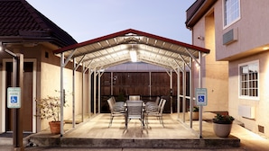 Un espace extérieur abrité avec une table et des chaises, un pot de fleurs et un panneau indiquant « Place de stationnement réservée ».