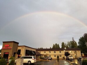 A Best Western Inn with a parking lot and a rainbow in the sky.