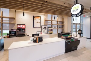 Una barra de desayuno moderna con un menú a la vista, una máquina de café y un dispensador de bebidas.
