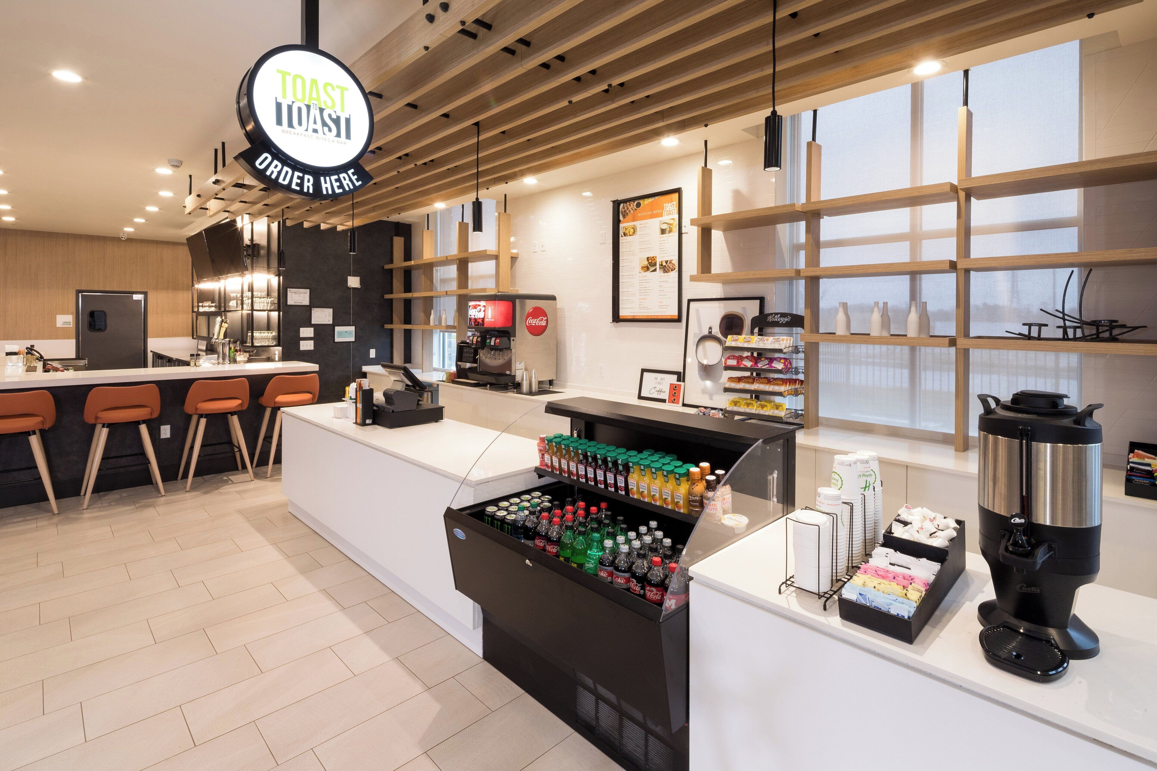 A modern cafe interior with a central counter, seating area, and a menu board.