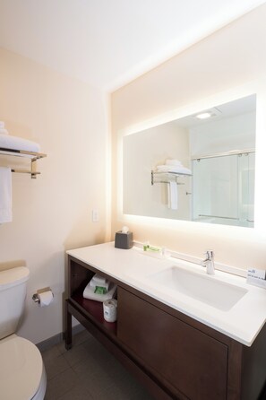 A modern bathroom with a white sink, a large mirror, and a towel rack. - Holiday Inn Kalamazoo West by IHG (Kalamazoo)