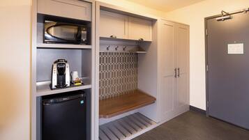 Una kitchenette compacta con microondas, cafetera y un refrigerador pequeño.
