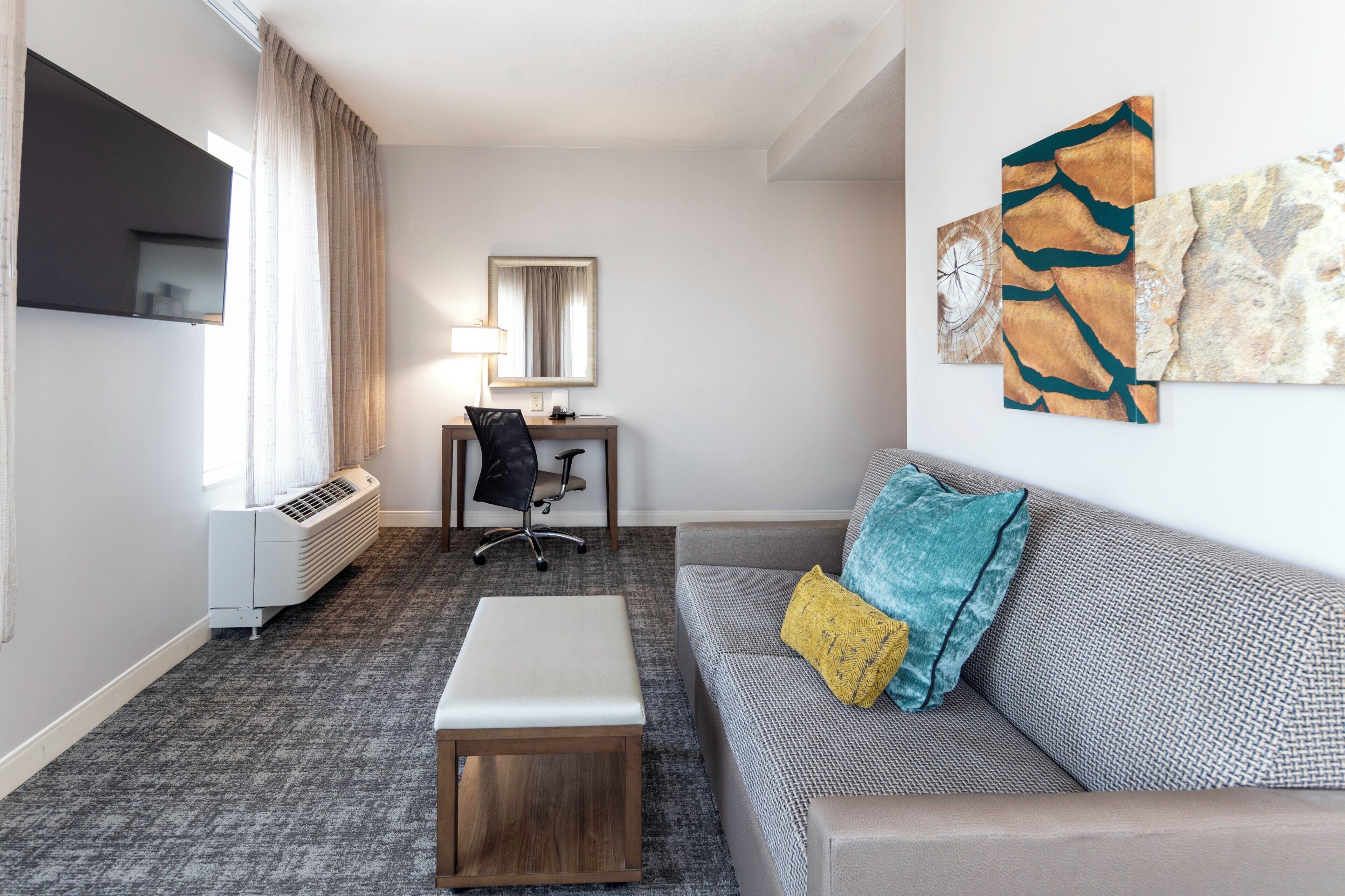 Ett hotellrum med ett skrivbord, en stol, en soffa och konstverk på väggen.
