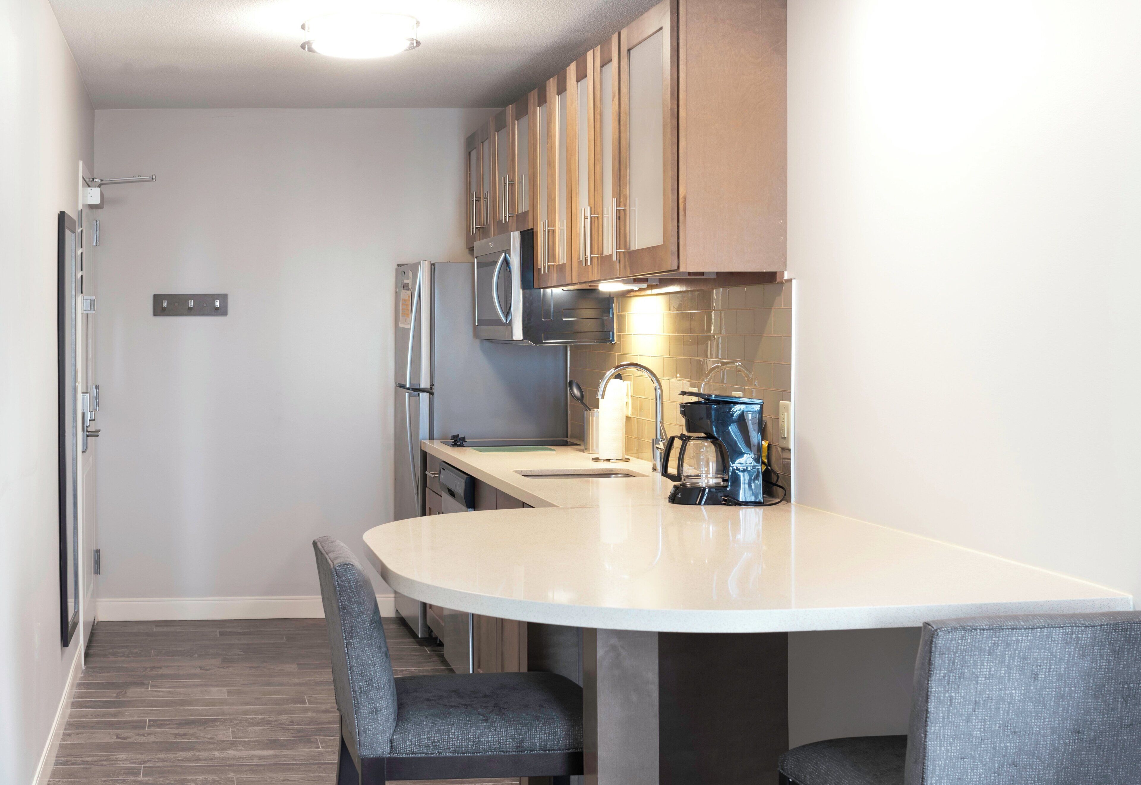 A modern kitchen with a white countertop, stainless steel appliances, and wooden cabinets.