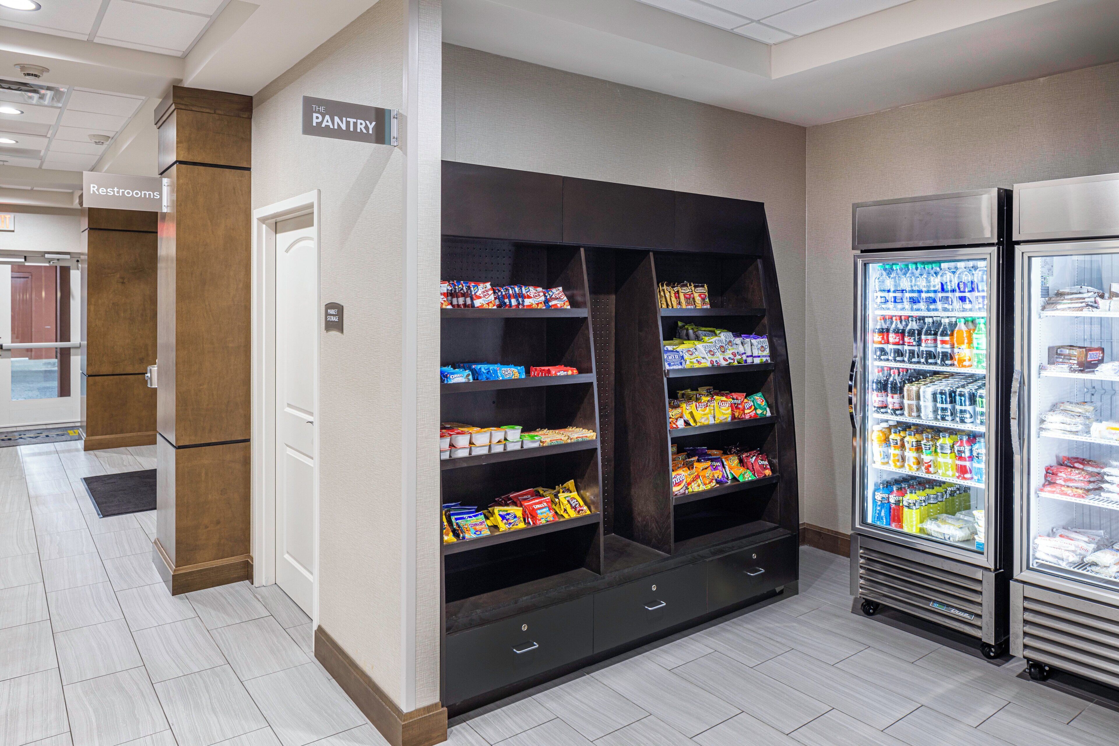 A pantry area with shelves stocked with snacks and beverages, a restrooms sign, and a market storage sign.