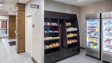 A pantry area with shelves stocked with snacks and beverages, a restrooms sign, and a market storage sign.
