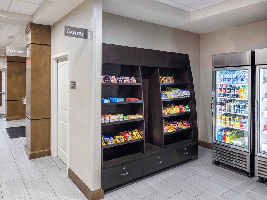 A pantry area with shelves stocked with snacks and beverages, a restrooms sign, and a market storage sign.
