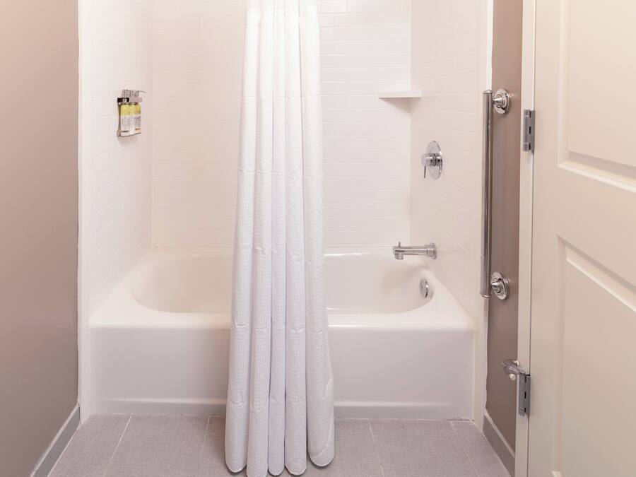 A bathroom with a bathtub, a shower curtain, and a toilet.