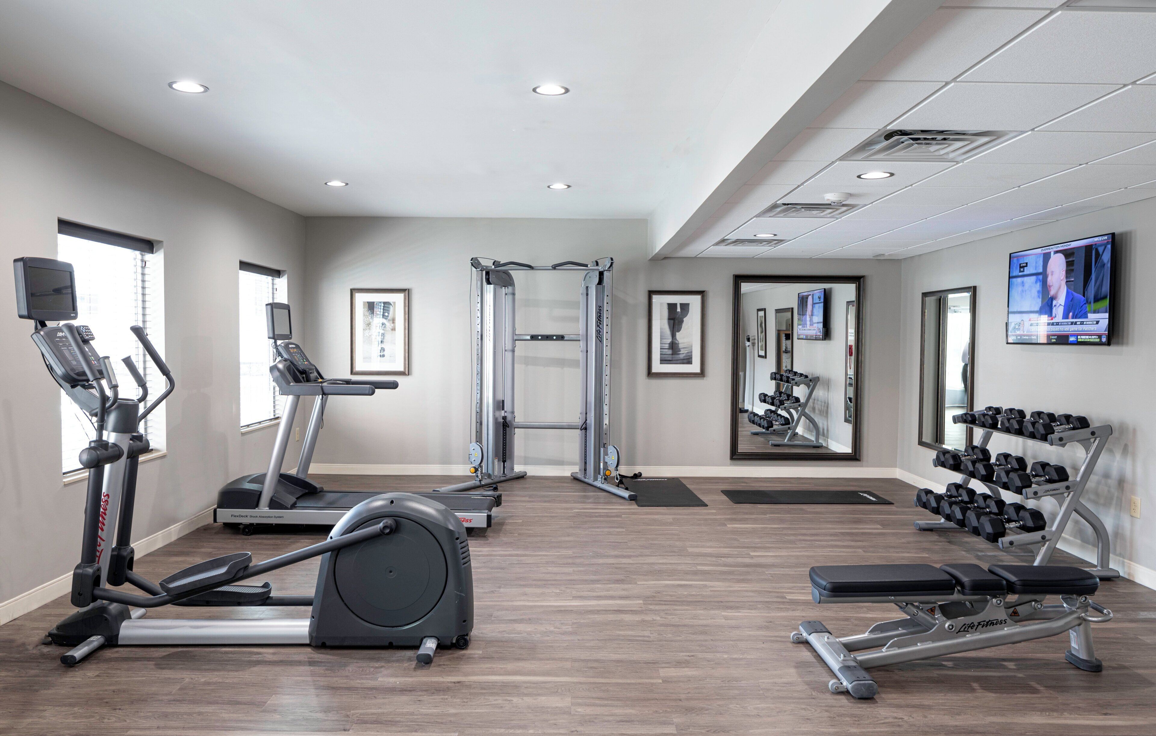 Une salle de sport équipée de machines de cardio, de matériel de musculation et d’un écran de télévision.