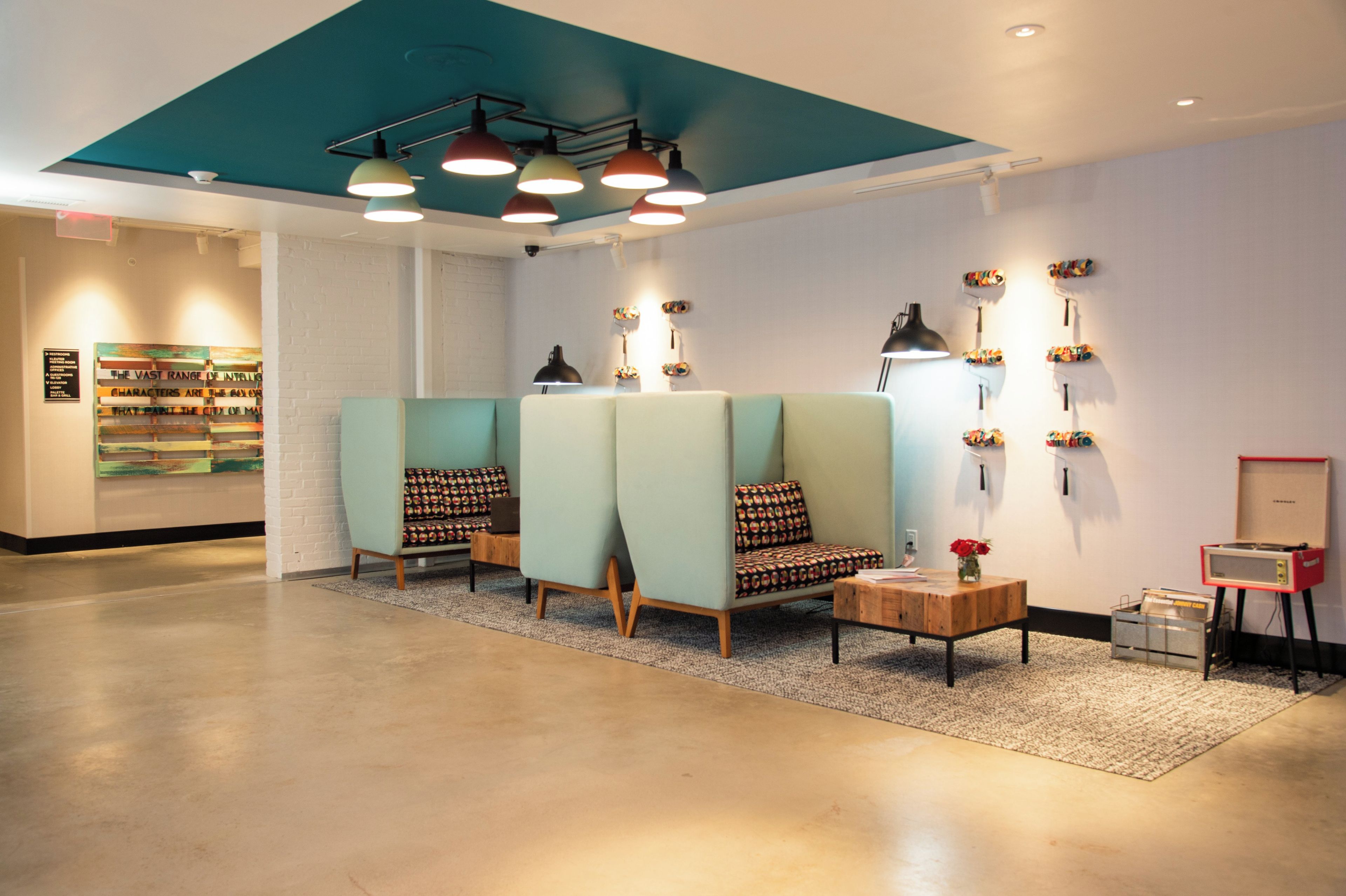 A lobby with seating areas, a reception desk, and a wall with a sign.