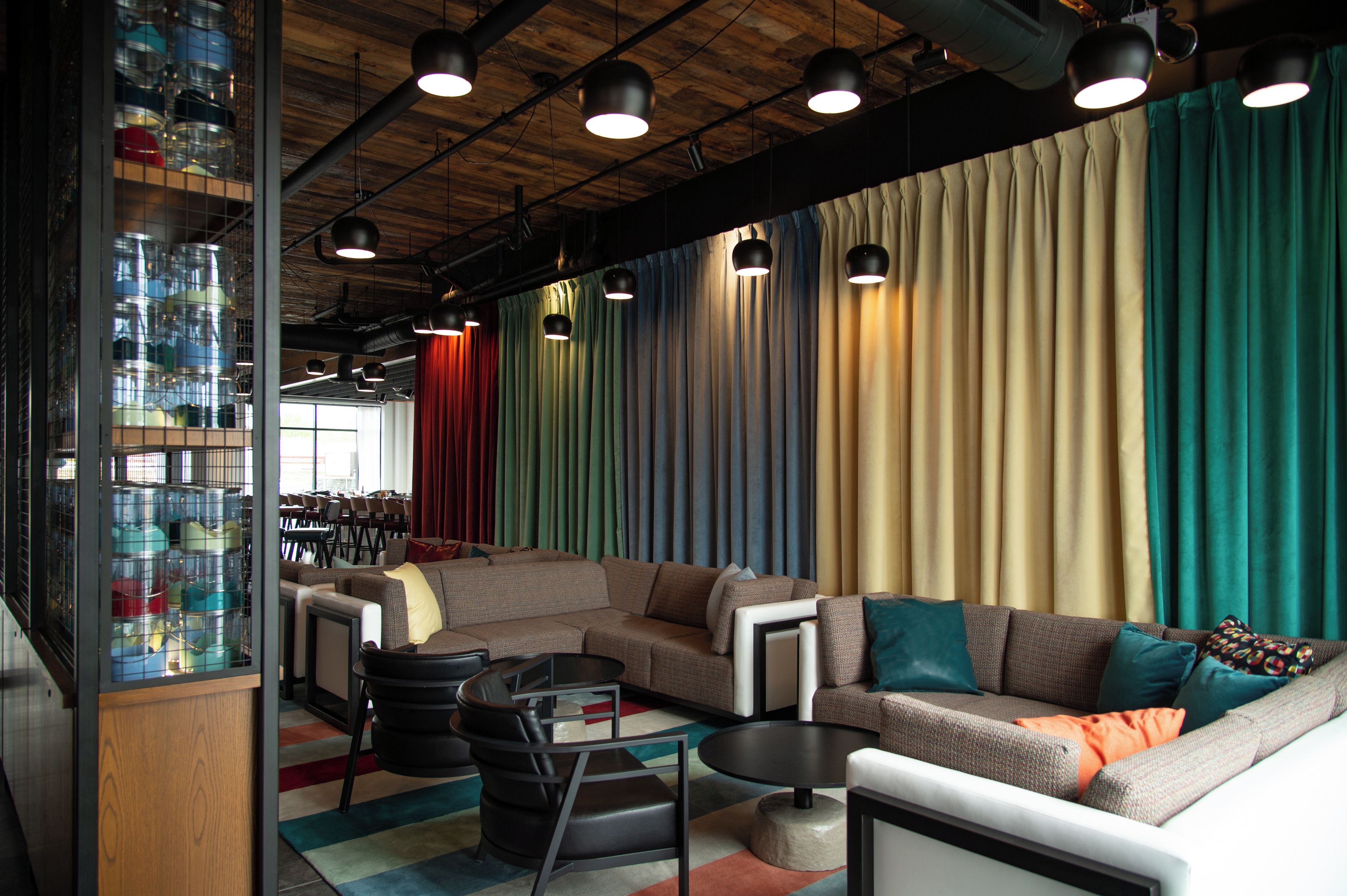 Un espacio lounge moderno con un sofá modular, una mesa de centro y una zona de bar con taburetes.