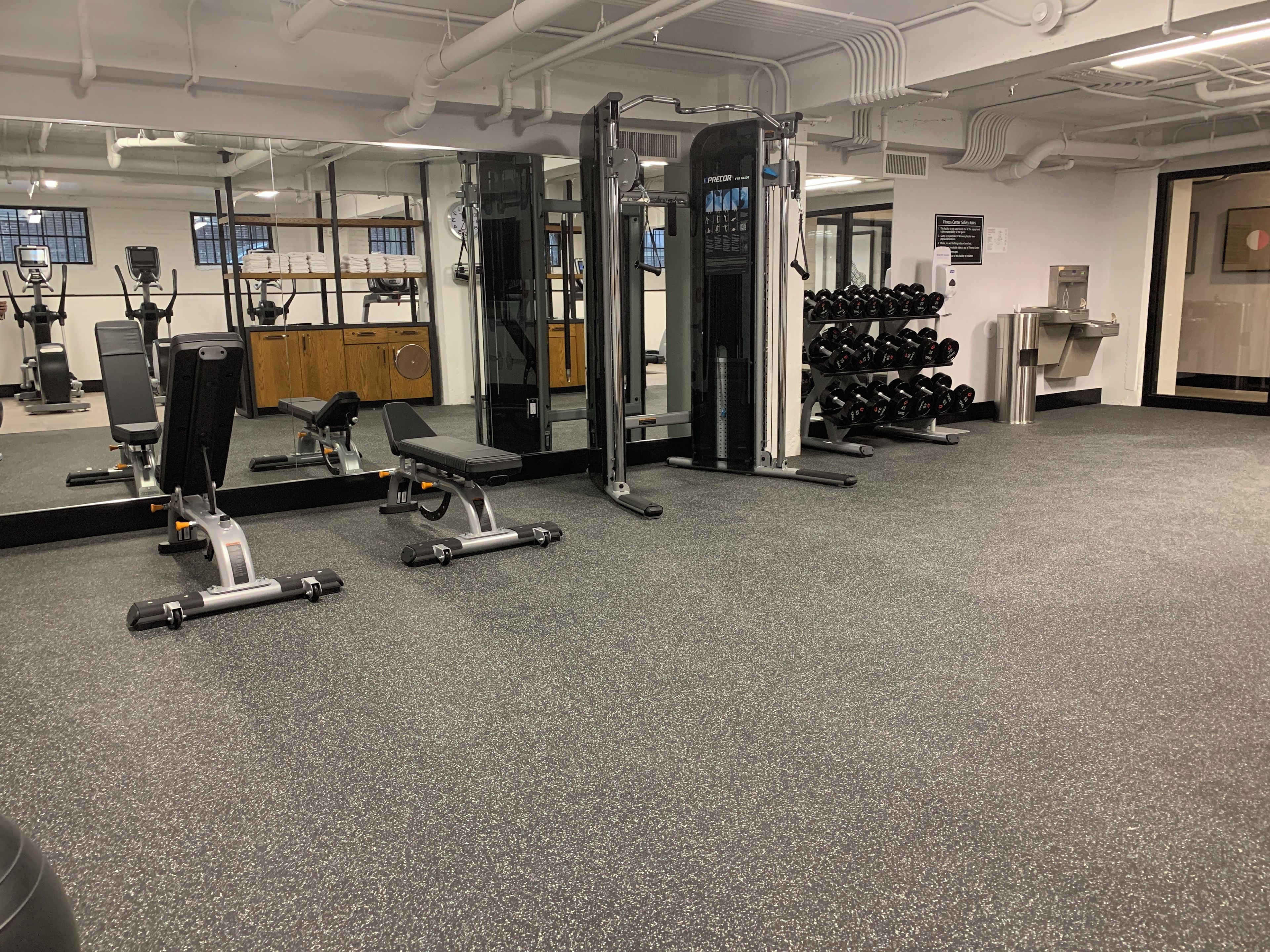 A gym with various exercise equipment, including a bench press, dumbbells, and a squat rack.