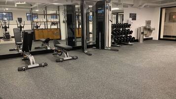 A gym with various exercise equipment, including a bench press, dumbbells, and a squat rack.