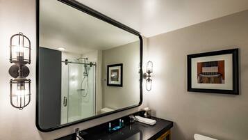 A modern bathroom with a large mirror, black countertop, and a framed picture on the wall.