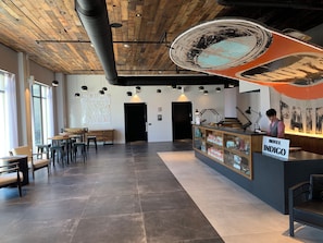 A hotel lobby with a wooden ceiling, a reception desk, and a seating area with tables and chairs. - Hotel Indigo Madison Downtown by IHG (Madison)